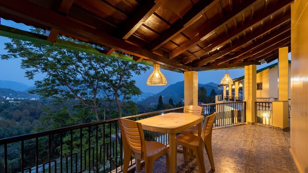 Un balcón con una mesa y sillas, un colgador de luces y vistas del paisaje circundante.