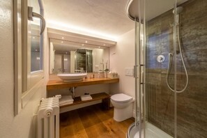 A modern bathroom with a glass-enclosed shower, a wooden vanity, a white sink, and a toilet.