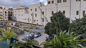 A balcony with potted plants, a view of a street with parked cars, and buildings with multiple windows and balconies. - Next to the massimo theater, beautiful apartment (Palermo)