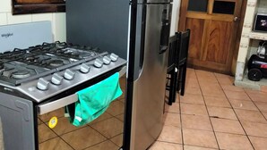 A kitchen with a stainless steel refrigerator, a gas stove, and a tiled floor.
