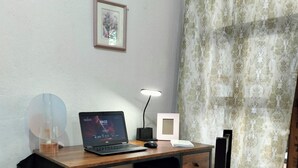 A small office space with a desk, chair, laptop, and a lamp.