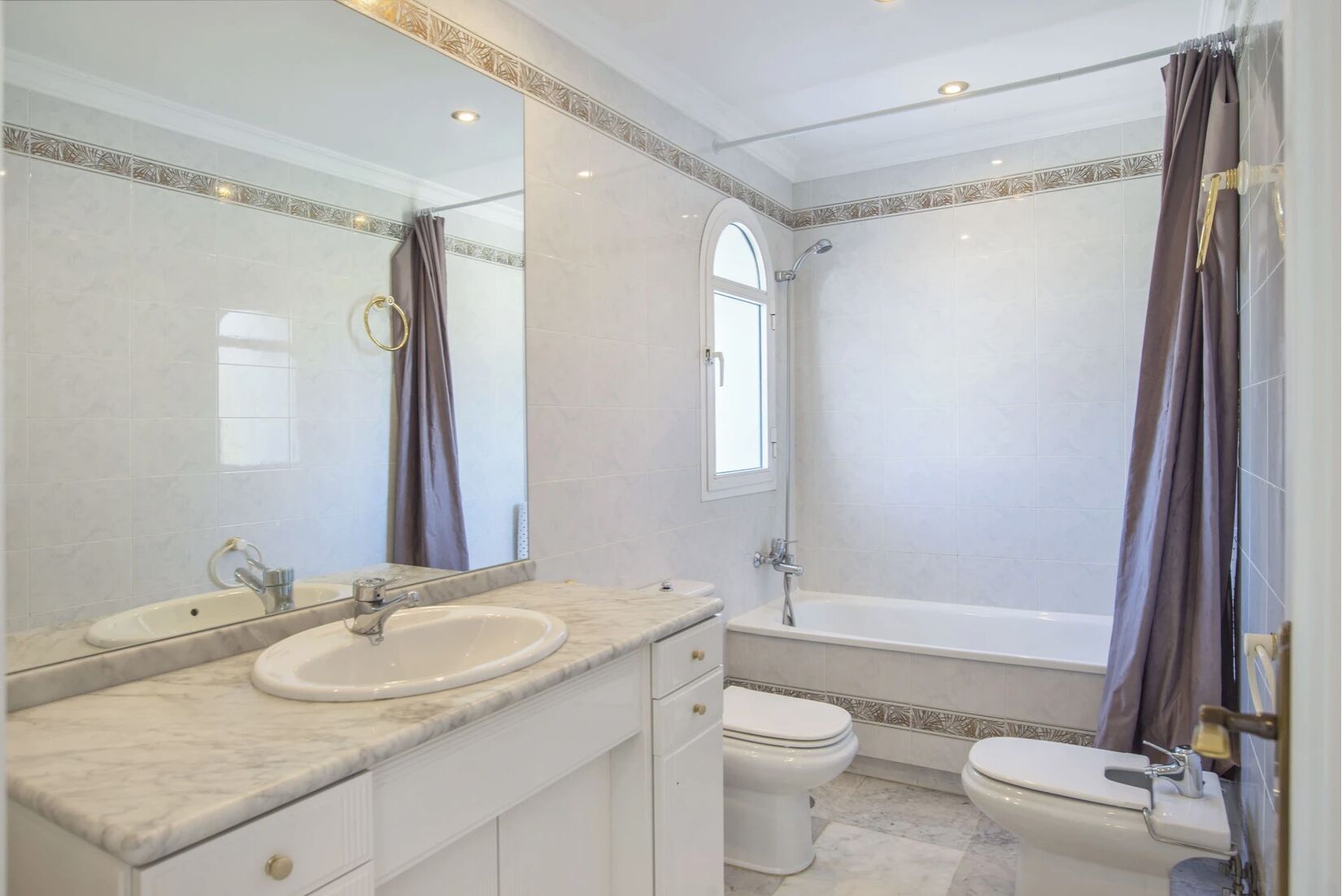 A bathroom with a large mirror, a sink, a toilet, and a bathtub.