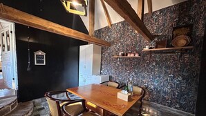 Un coin repas avec une table et des chaises en bois, un tableau noir avec des inscriptions et un mur orné d’un motif.