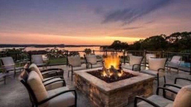 A fire pit surrounded by outdoor seating, overlooking a body of water during sunset. - Bogey Bungalow-Four Seasons-1BD/1BA/Balcony/Pool/Golf-2PP (Lake Ozark)