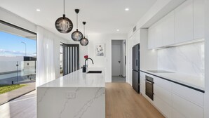 A modern kitchen with a large island, white cabinetry, and pendant lighting. - Elysium - Skennars Head (Skennars Head)