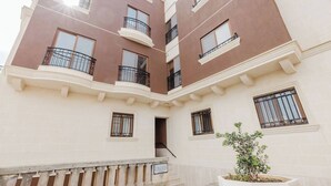 Un edificio residencial de varios pisos con balcones, una escalera y una planta en maceta.