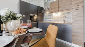 Una cocina moderna con armarios oscuros, encimera de madera y salpicadero con estampado de corazón.