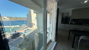 A balcony with a clear view of a coastal town, a modern kitchen, and a dining area.