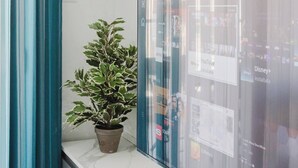 Um interior moderno com uma planta em vaso sobre um balcão de mármore, uma divisória de vidro com telas de instalação de aplicativos e uma cortina azul-turquesa.