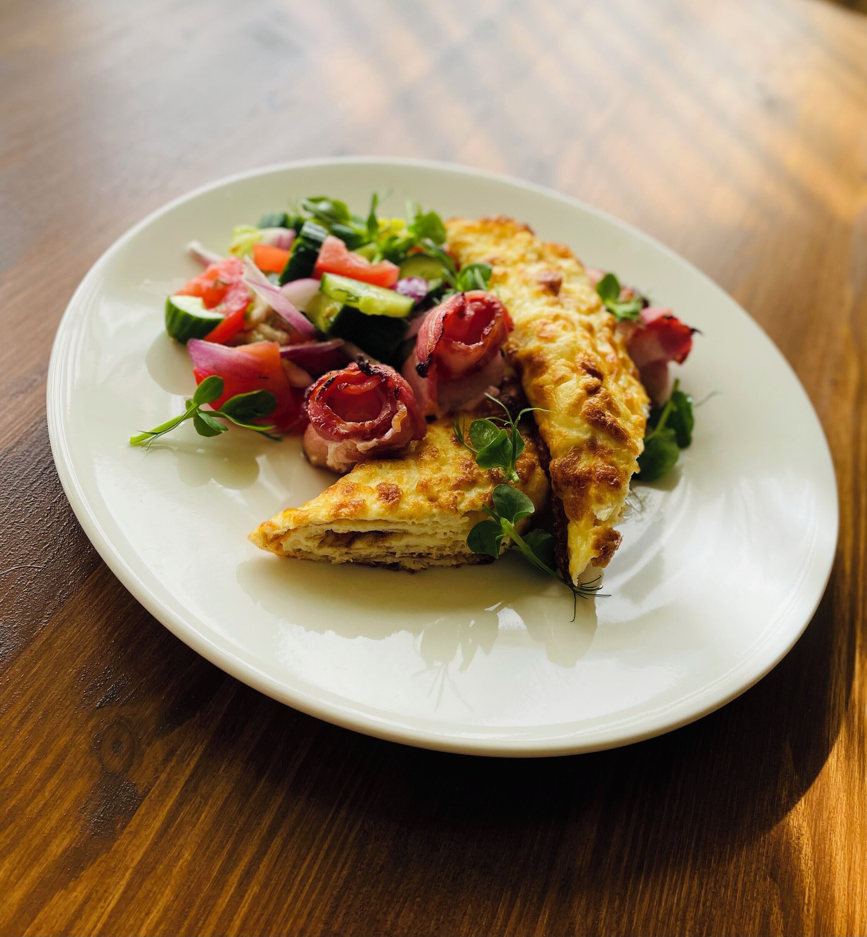 A plate with a folded omelette, a fresh salad, and smoked salmon.