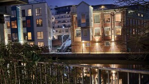 A nighttime view of a riverside building with multiple floors, featuring a mix of modern and traditional architecture. - The Penthouse in Norfolk (Norwich)