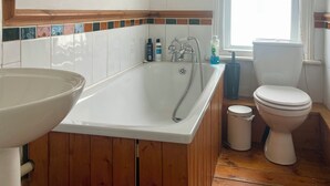 A bathroom with a wooden bathtub, a sink, a toilet, and a window with blinds. - Charming Brighton Townhouse (Brighton and Hove)