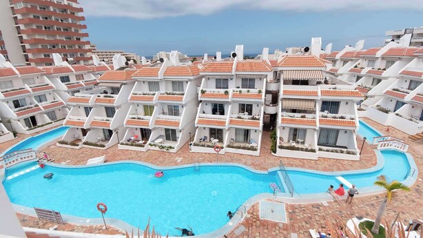 Un hotel moderno con una piscina central rodeada por edificios de varios pisos con balcones.