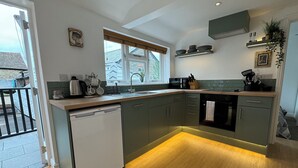 A modern kitchen with a dishwasher, sink, and a window with blinds.