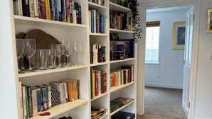 A well-organized bookshelf with various books and wine glasses.