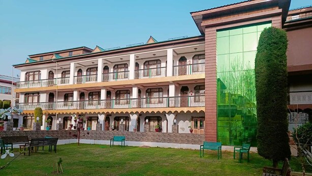 Un edificio de varios pisos con balcones, césped verde y asientos exteriores.