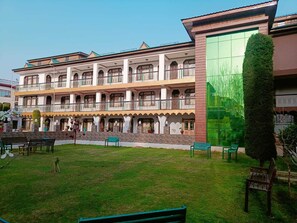 A multi-story building with balconies, a green lawn, and outdoor seating. - New Kashmir Hill Town (Srinagar)