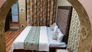 Un dormitorio con cama, cortinas y papel tapiz estampado.