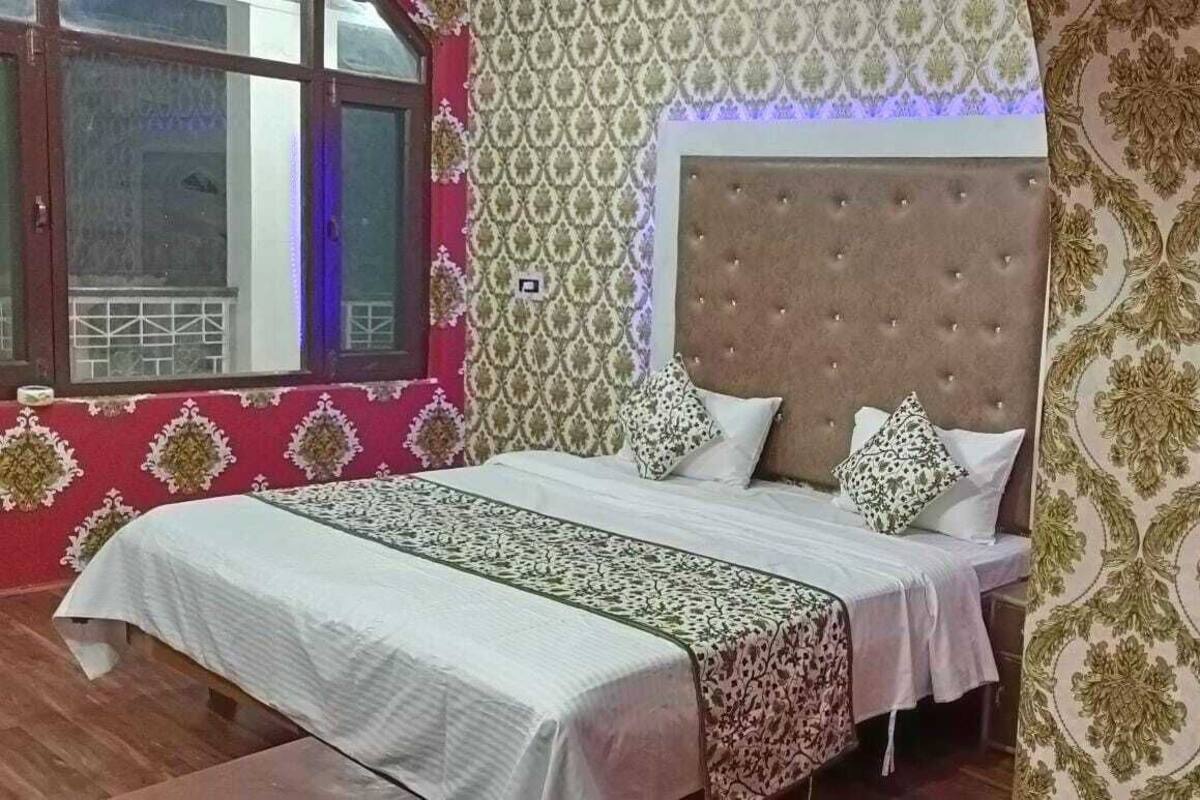 Un dormitorio con cama, papel tapiz estampado y ventana con vistas.