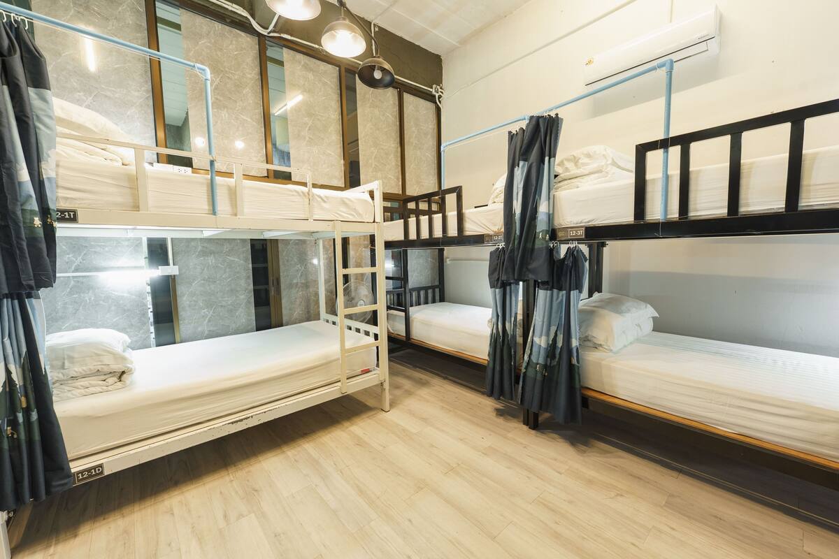 Une chambre de dortoir avec des lits superposés, un plancher en bois et un appareil de climatisation.