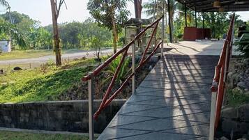 A covered outdoor staircase leading to a building with a metal roof, surrounded by greenery and trees.