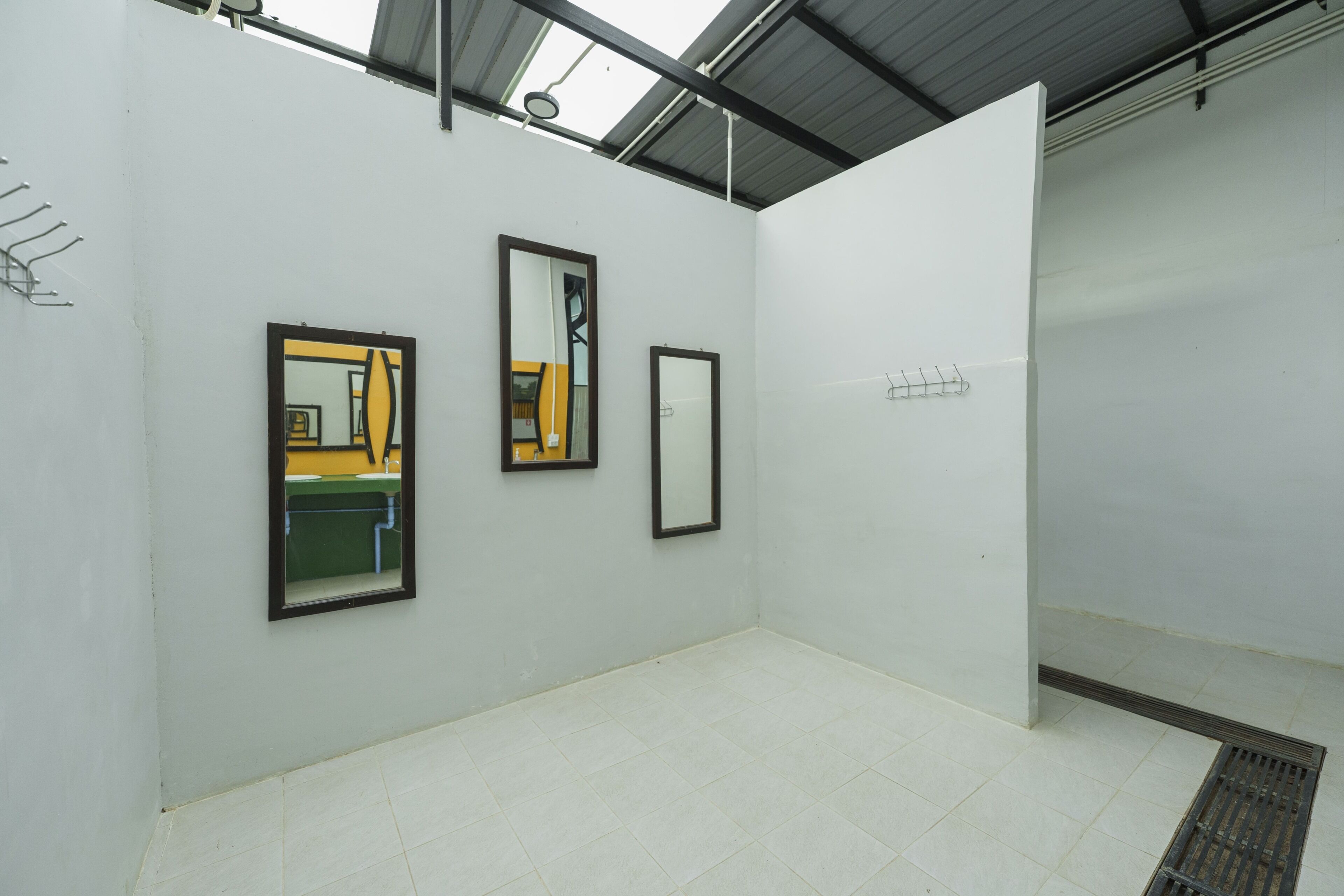 Una galería con paredes blancas, tres espejos enmarcados y suelo de baldosas.