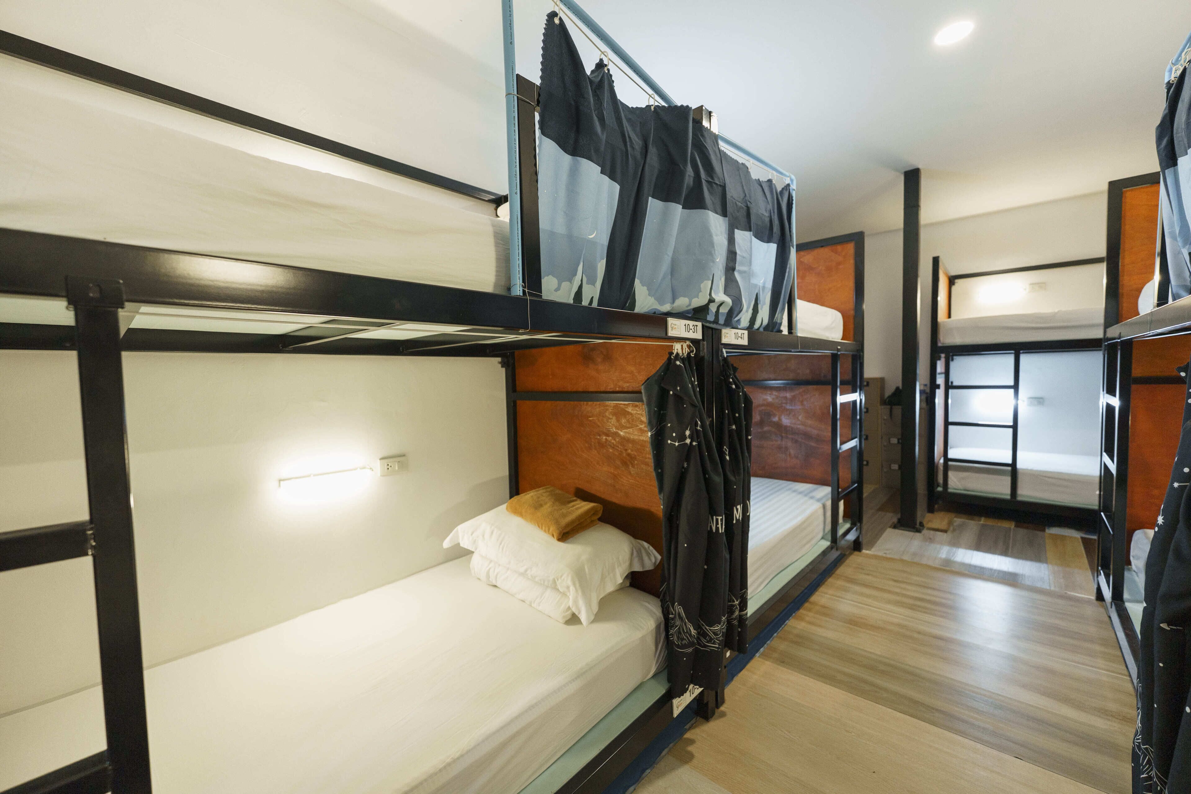 A bunk bed room with a wooden floor, a headboard, and a window.