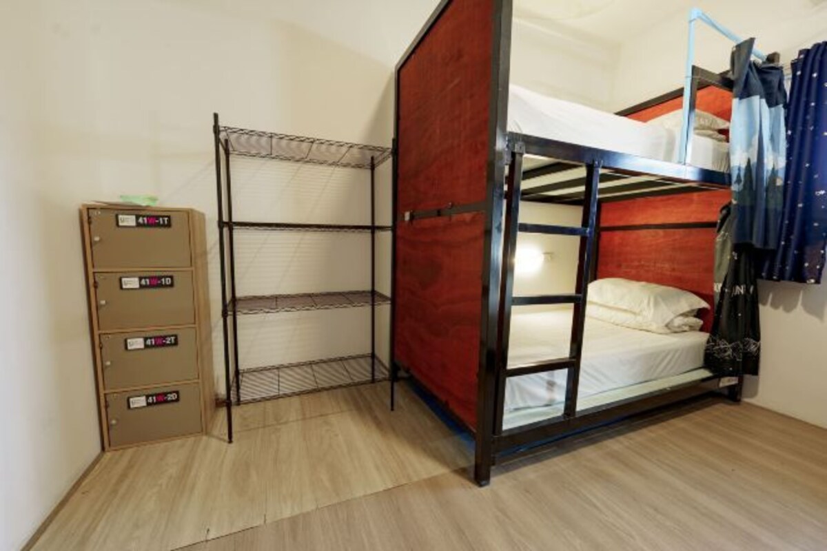 A bunk bed room with a metal frame, a wooden cabinet with labels, and a metal shelf unit.