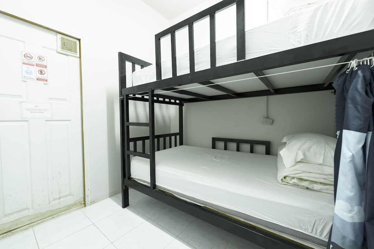Un lit superposé avec un matelas et des oreillers, une porte avec une pancarte et un rideau.