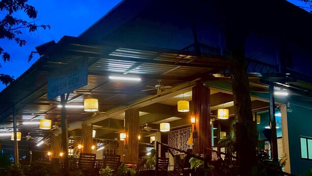 An outdoor seating area with tables and chairs, under a covered roof with hanging lights. - Green Gen Hotel Phuket (Ratsada)