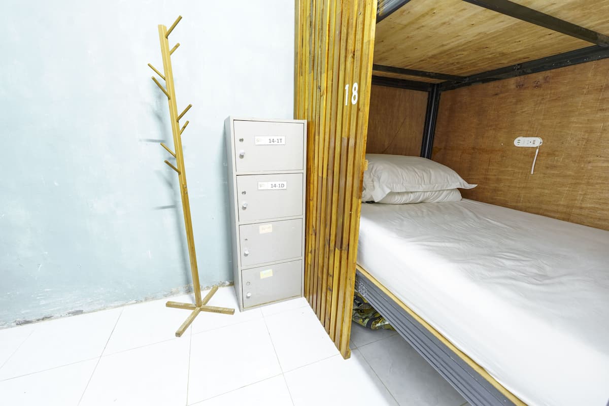 Une pièce comprenant un lit, un classeur métallique et une échelle en bois.