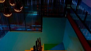 A staircase with a wooden handrail and a metal railing, leading to a landing with a shoe rack and a window with a view of the outside. - Green Gen Hotel Phuket (Ratsada)
