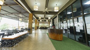 An indoor space with a reception desk, seating area, and large windows. - Green Gen Hotel Phuket (Ratsada)