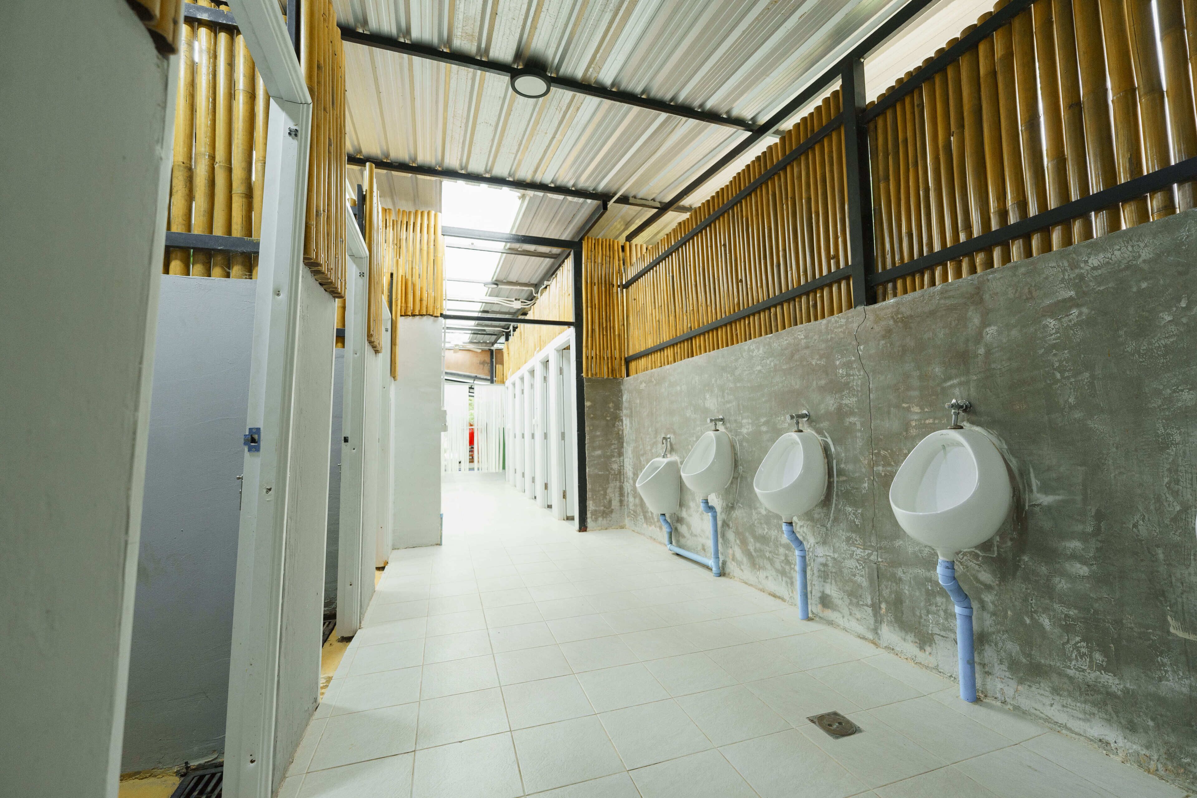 A restroom with multiple urinals, a tiled floor, and a concrete wall.