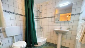 Une salle de bain équipée de toilettes, d’un bidet, d’un lavabo et d’une douche.