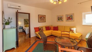 A living room with a sofa, chairs, a glass table, a chandelier, and artwork on the walls. - Apartment Azzuro Bay 2 (Jadranovo)