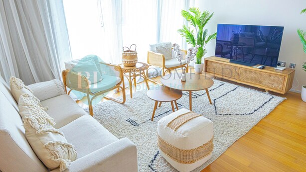 Un salon moderne comprenant un canapé, une table basse, des fauteuils et un téléviseur.