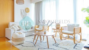 Un salon comprenant un canapé, deux fauteuils, une table ronde et un luminaire suspendu.