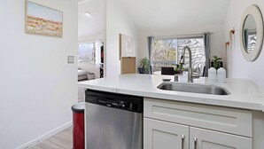 Een moderne keuken met een vaatwasser, een spoelbak en een raam met gordijnen.