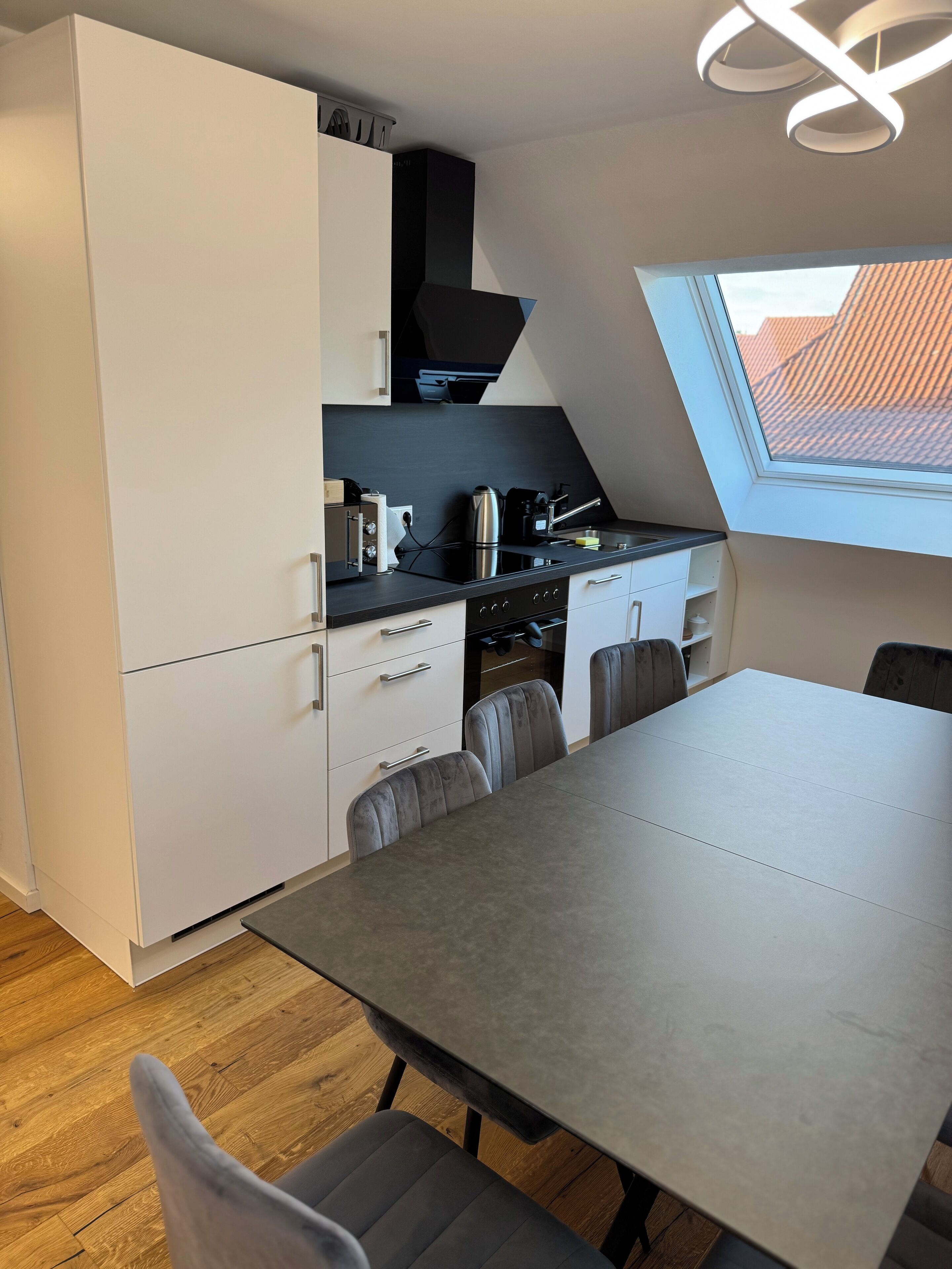 Una cocina compacta con comedor, que incluye un horno empotrado, una estufa y una ventana sobre el fregadero.