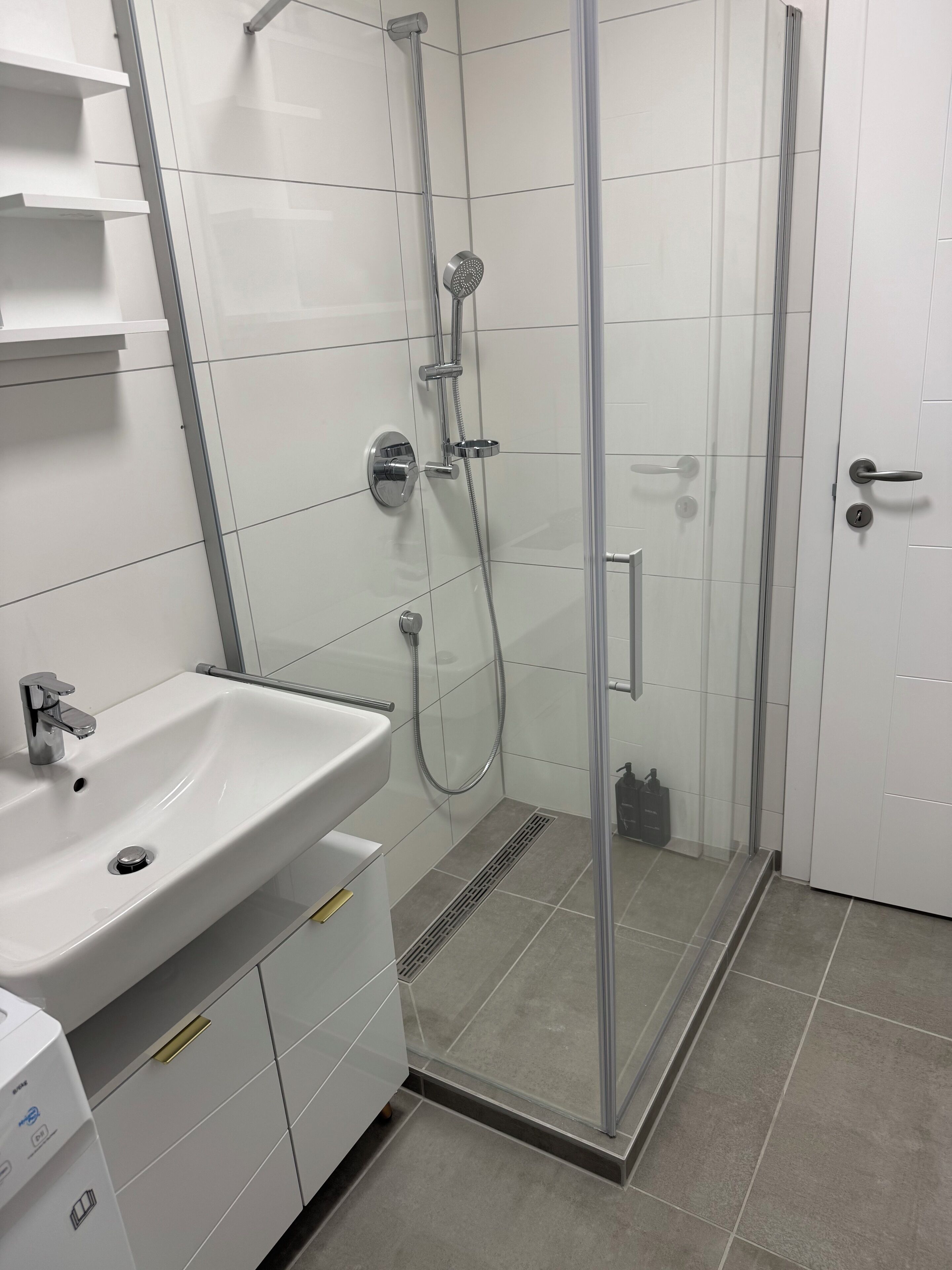 Un baño moderno con ducha acristalada, lavabo blanco y retrete.