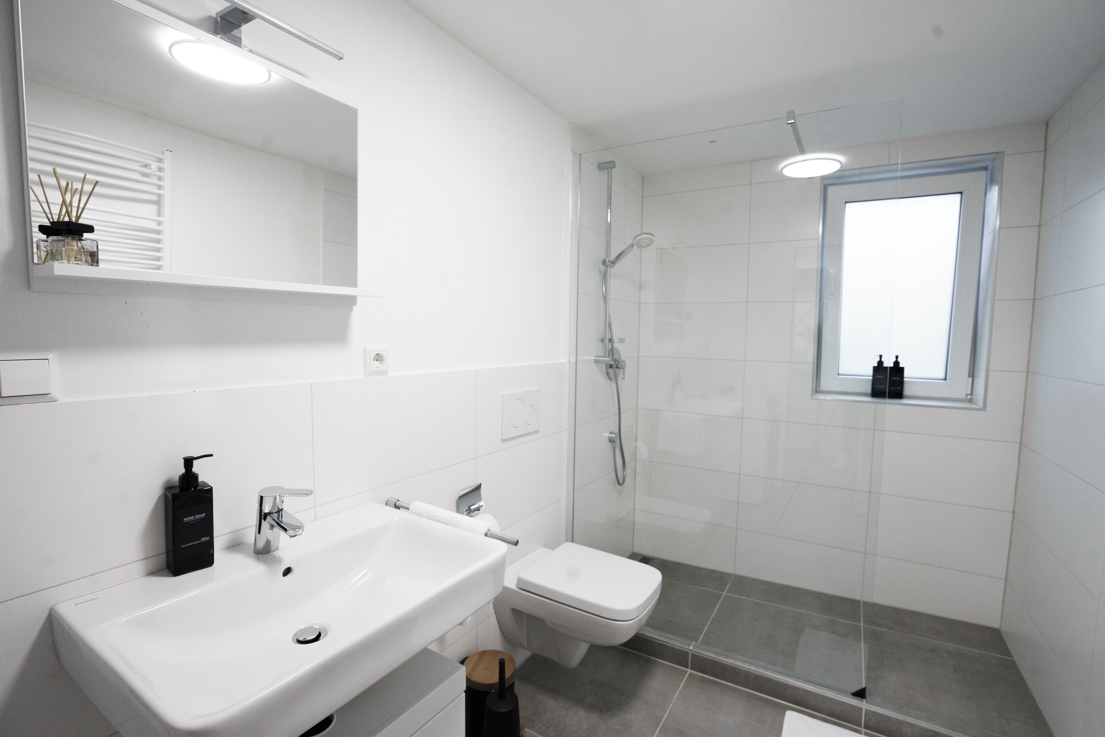 Ein modernes Badezimmer mit einem weißen Waschbecken, einer Toilette und einer Duschkabine.