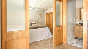 Un dormitorio con cama, un armario de madera y un baño con lavabo y espejo.