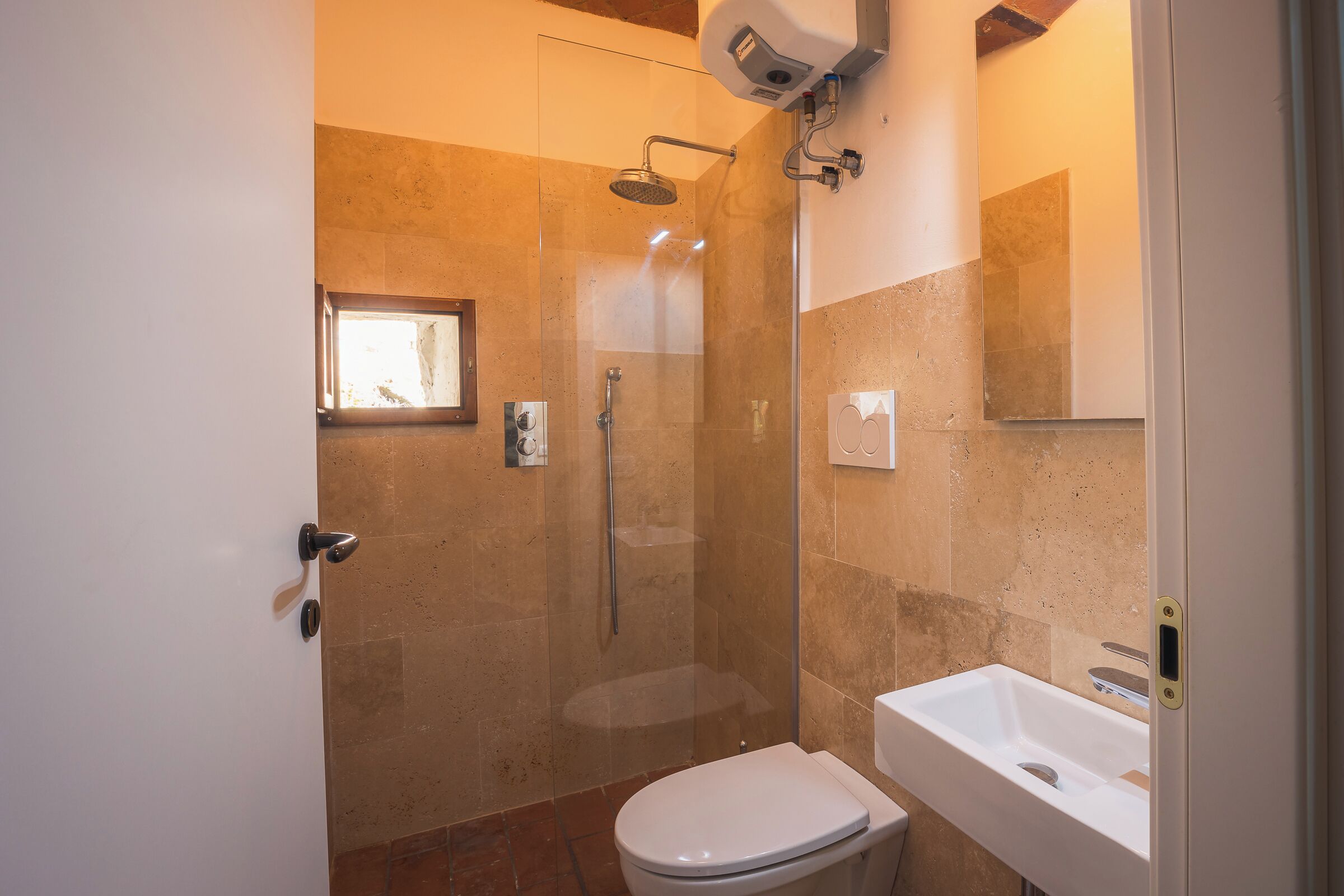 A bathroom with a glass-enclosed shower, a white toilet, and a sink.