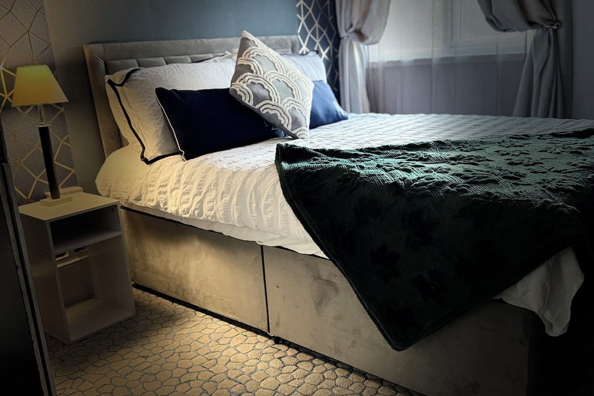 Une chambre à coucher avec un lit, une table de chevet, une lampe et un tapis à motifs.