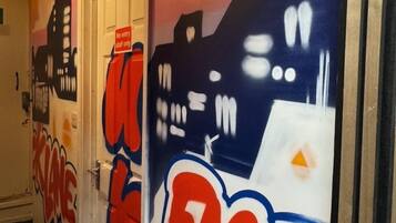 En korridor med dörrar som är dekorerade med konstverk i graffiti-stil och en skylt med texten ”Ingen tillträde”.