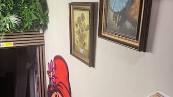Un pasillo con pared verde, un cuadro enmarcado y un recorte de un personaje de caricatura.