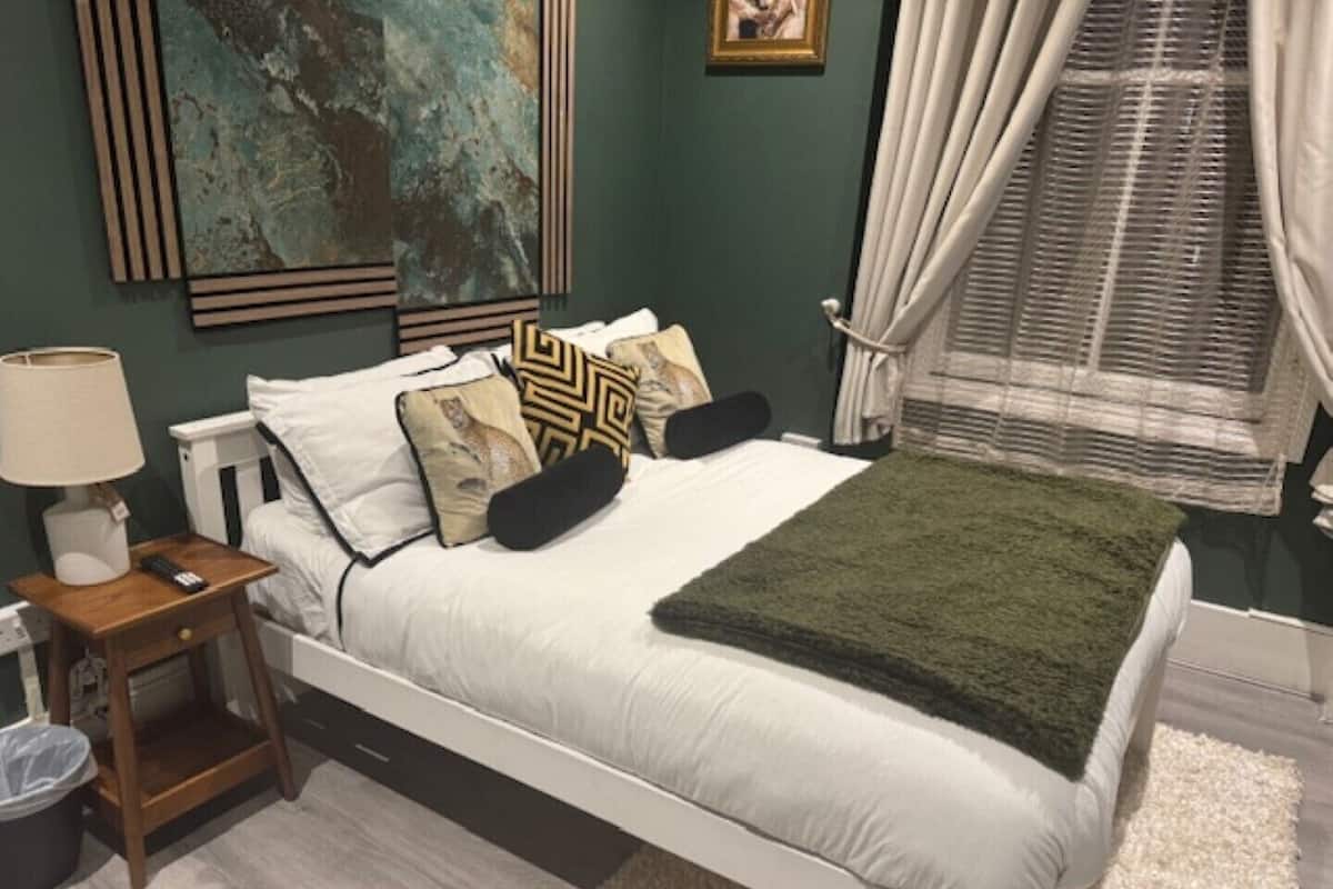 Une chambre à coucher avec un lit, une table de chevet, une lampe et un tableau au mur.