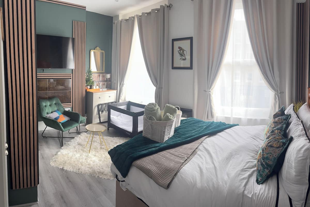 Une chambre d’hôtel équipée d’un lit, d’un bureau, d’une chaise, d’une télévision, d’un miroir et d’une fenêtre avec des rideaux.