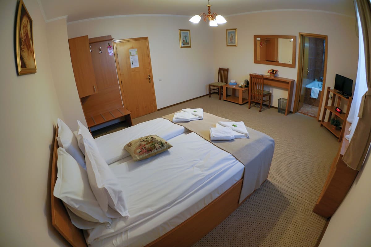 Habitació d'hotel amb dos llits, un escriptori, una cadira, un televisor i un bany.